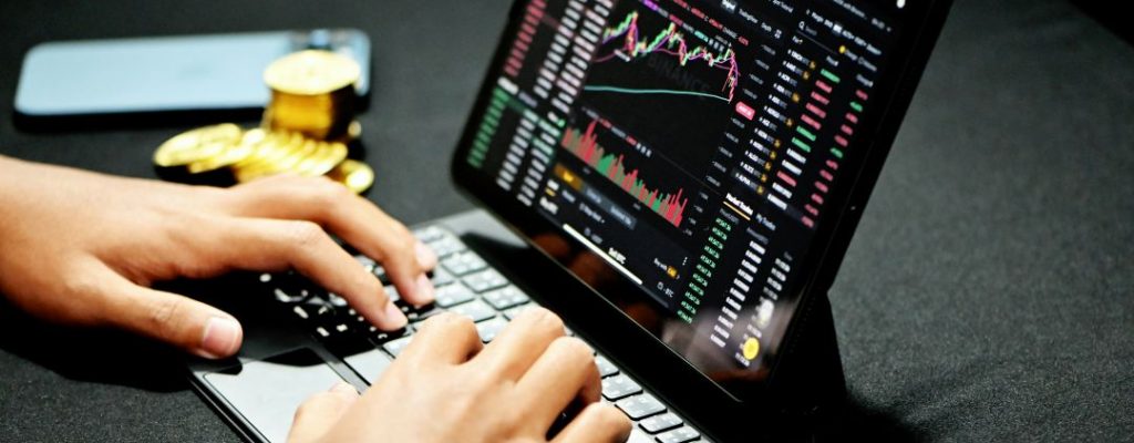 hands at a computer displaying stock prices