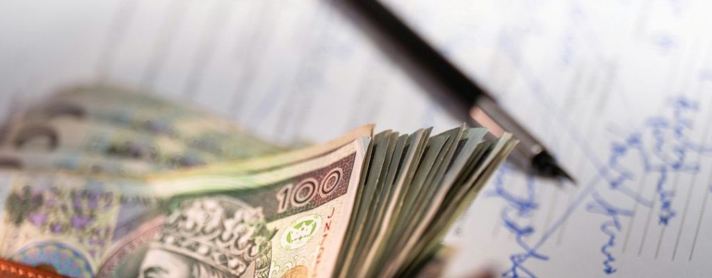 money in a wallet, laid on a note pad with a pen