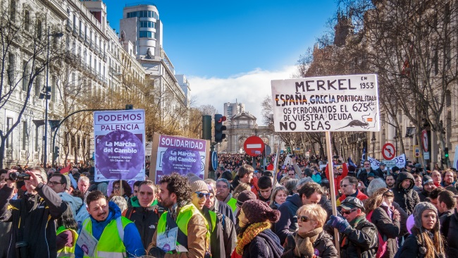 Manifestación del partido Podemos en Madrid, "La marcha del cambio". Vista de la calle de Alcalá desde Cibeles. La pancarta reza: "Merkel, en 1953 España, Grecia, Portugal, Italia, etc. os perdonamos el 625% de vuestra deuda. No seas "